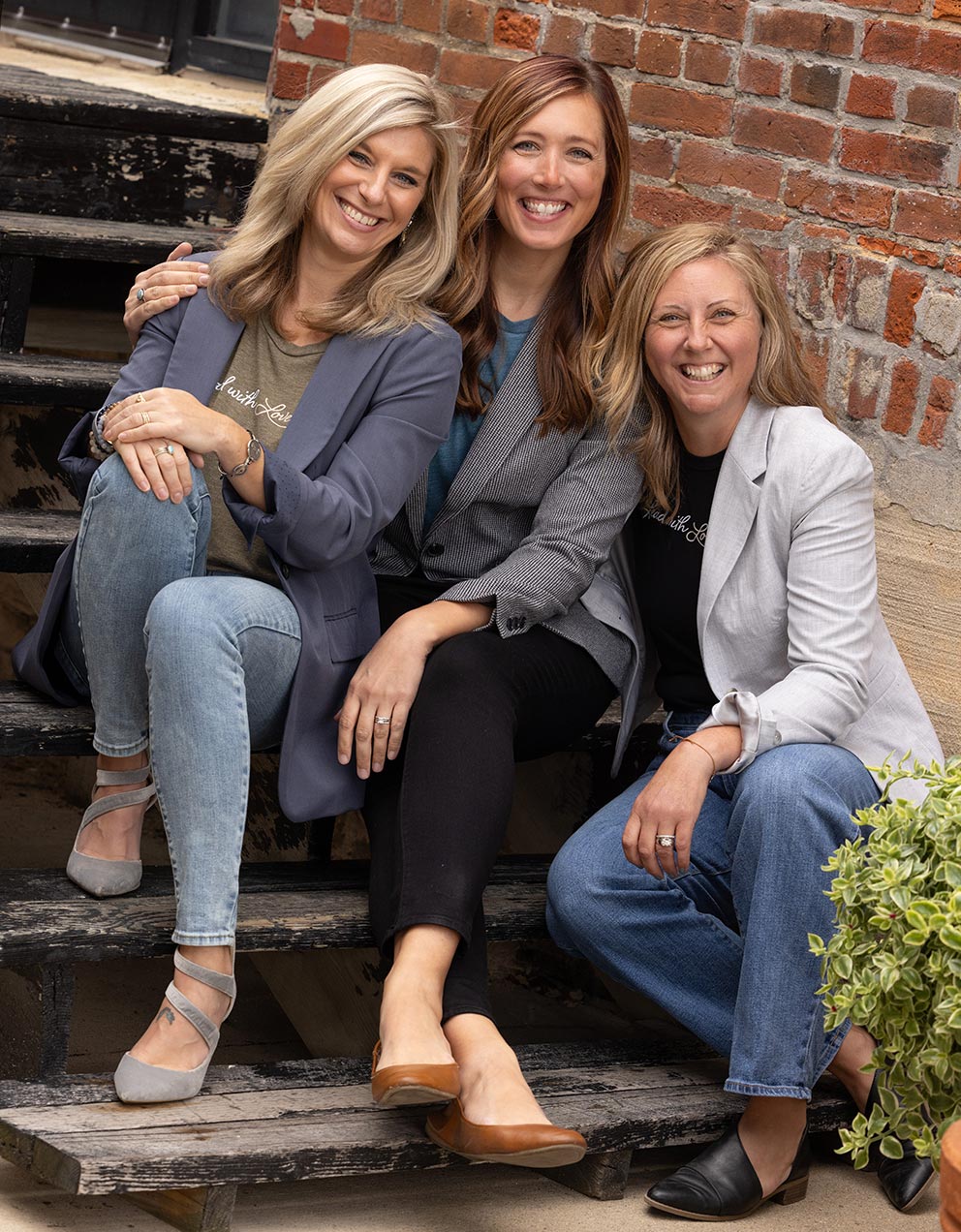 Lindsay, Sara, and Brooke pose together on steps in front of a brick facade