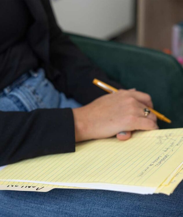 close up of a hand with a pencil and notepad