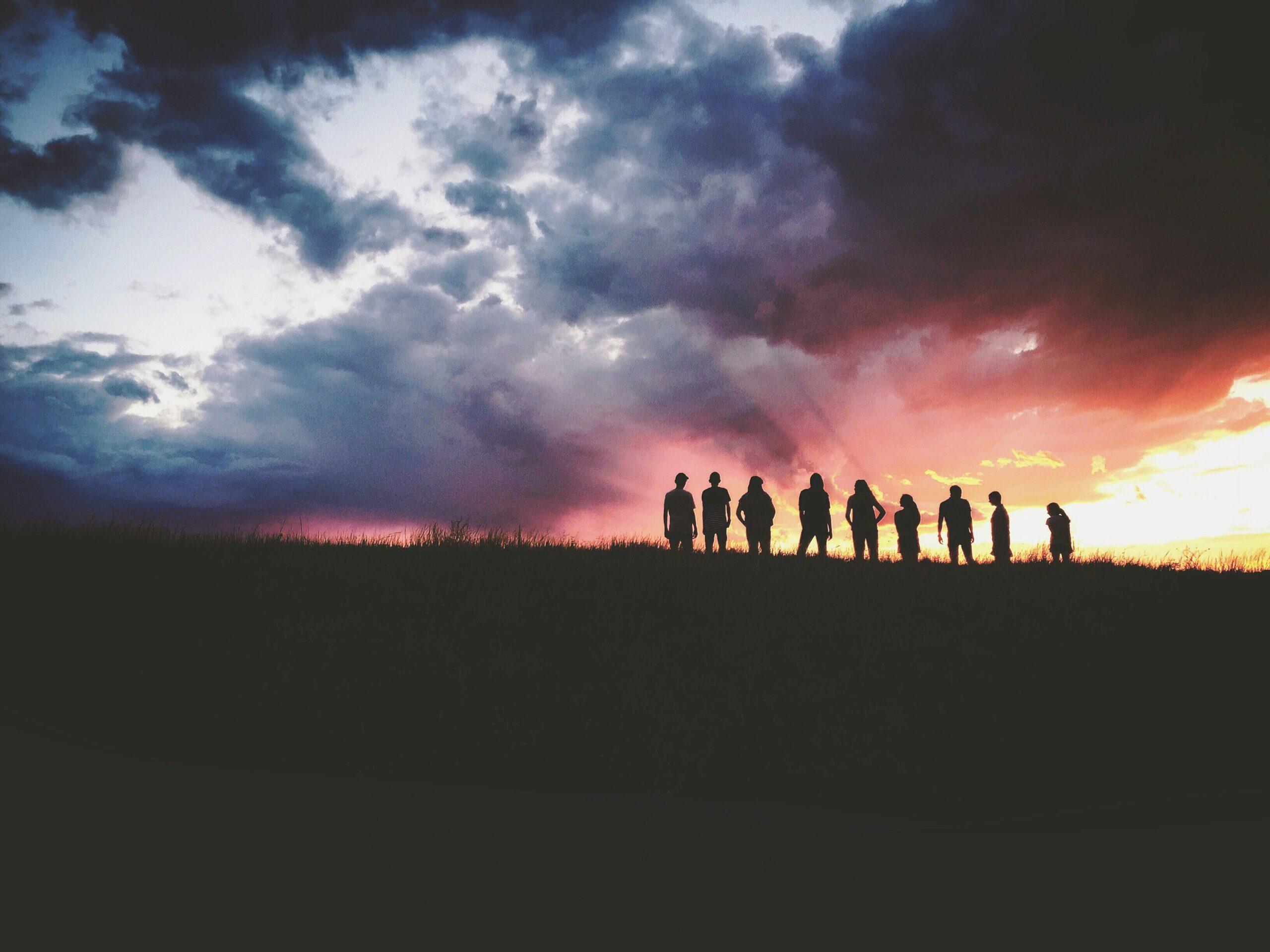 Several people moving outside during sunset